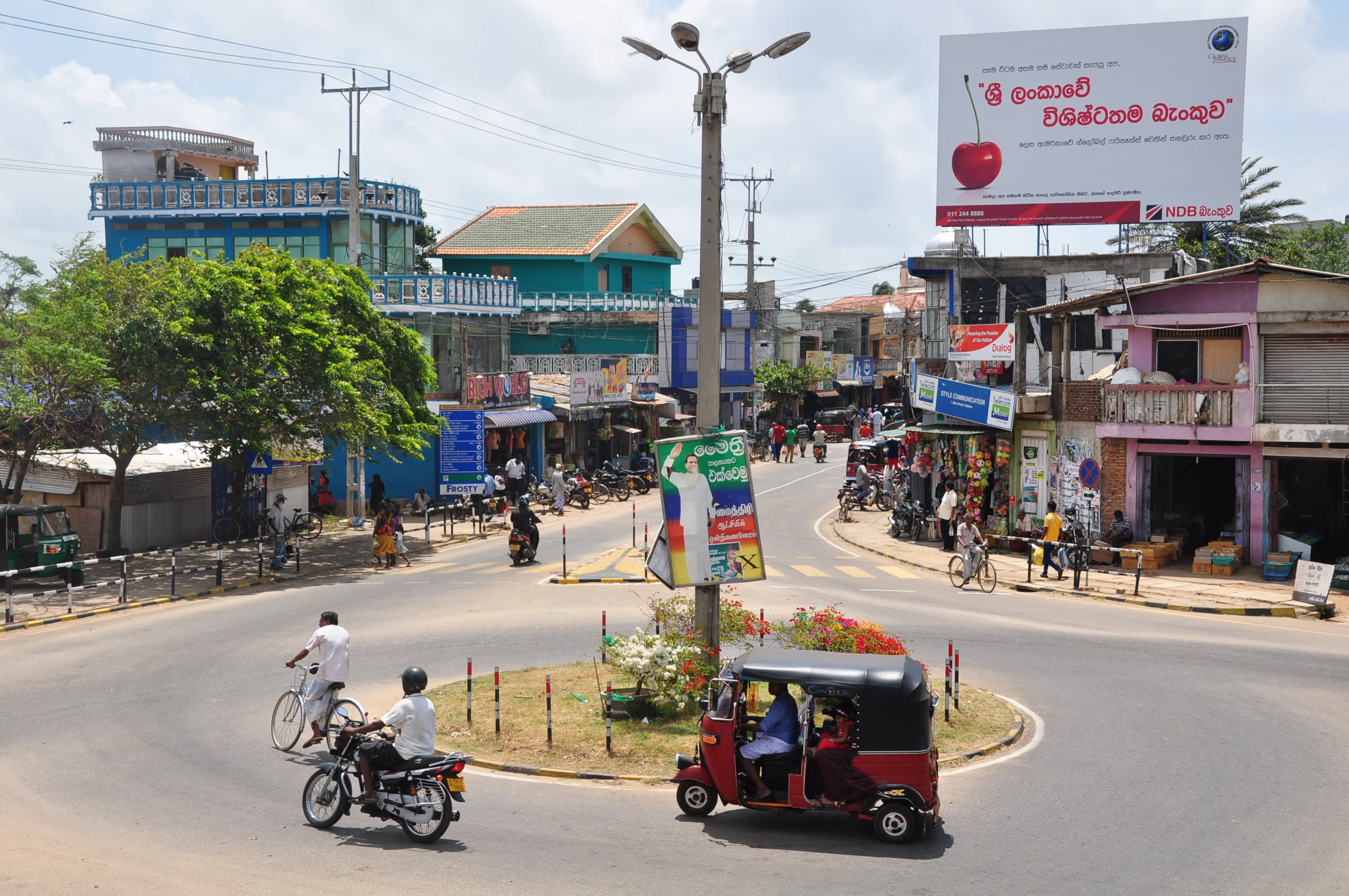 A busy roundabout in a Sri Lankan town, with three-wheelers and motorbikes.
